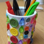 A pencil pot decorated with gems and buttons.