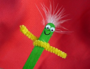 green stick puppet with yellow pipe cleaner arms