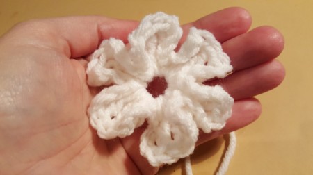 A crocheted petaled flower in a hand.