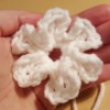 A crocheted petaled flower in a hand.