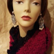 A burgundy and black scarf displayed on a mannequin head.