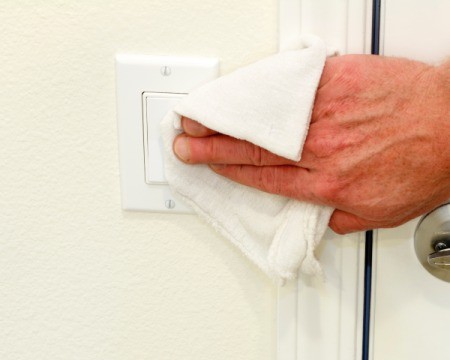 Cleaning a lightswitch near a door.