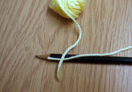 Yarn Flower Hair Clip - take the end of the other yarn and lay across the piece lying along the pencil