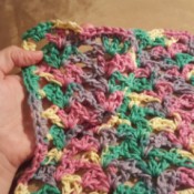 Lacy Crocheted Dishcloth - hand holding finished multicolor cloth