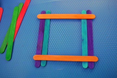 still laying out the frame prior to gluing, adding an orange stick across the top and bottom of the parallel blue and purple stick sets
