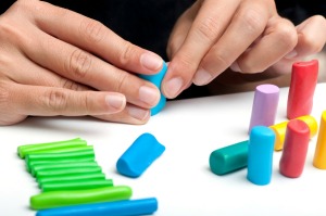 A photo of hands molding multi-colored polymer clay.