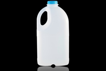 A single plastic 1/2 gallon milk jug against a black background.