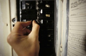 human hand flipping the switch on the circuit breaker.