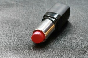 Opened tube of Red Lipstick on black leather surface