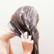 Back view of a woman's sudsy hair as she washes it.