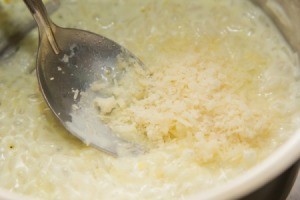 Adding Parmesan cheese to a pot of risotto.