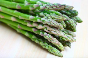 Pile of asparagus spears against a white background