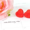 Close-up of large desk calendar with March 13th marked as Wedding with two red hearts and a large pink roses laying on the calendar.