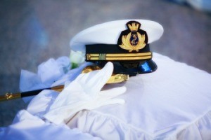 Soldiers hat and glove on a white fabric surface (possibly a pillow)