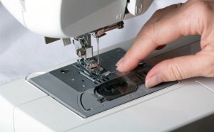 Close-up of a sewing machine with female had touching the standard sewing plate