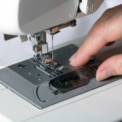 Close-up of a sewing machine with female had touching the standard sewing plate