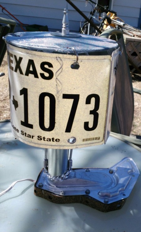 A lamp made with a license plate and other auto parts.