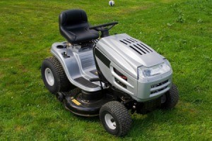 Silver and black riding lawn mower against mown grass background