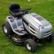 Silver and black riding lawn mower against mown grass background