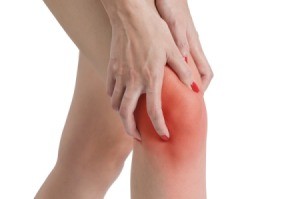 Close up of woman's hands clasping red knee in pain