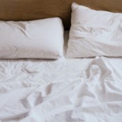 Unmade bed with rumpled white sheets