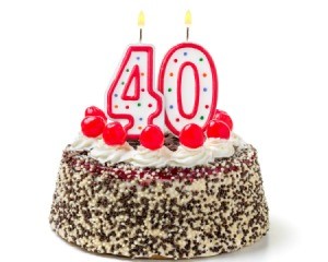 Burning candles shaped like the number 40 on a cake against a white background