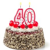 Burning candles shaped like the number 40 on a cake against a white background