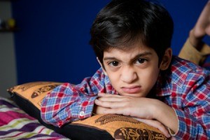 Young boy laying on a bed and wrinkling his nose