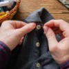 Man's hands sewing button on shirt