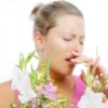 Woman sneezing with flowers in the foreground.