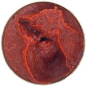 Top view of tomato paste can with a spoonful of paste removed against a white background