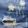 Close up image of a pair of jeans with rips, runs, and shredded areas