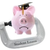 Frowning piggy bank wearing graduation cap being pressed by a metal clamp labelled "Student Loans"
