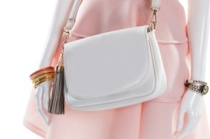 Close up of a white leather Purse on a mannequin wearing a pink dress.