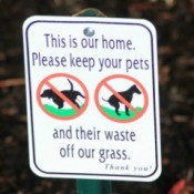 Close up of sign reading, "This is our home  Please keep your pets and their waste off our grass."