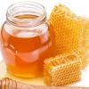 Jar of honey, two honeycomb, and spilled honey against a white background