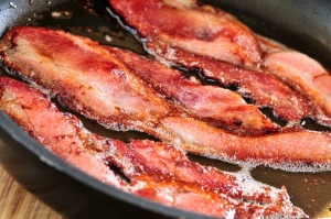 Several pieces of backing laying flat while sizzling in frying pan