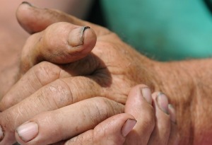 Close up of clasped hands with dirt imbedded under the fingernails