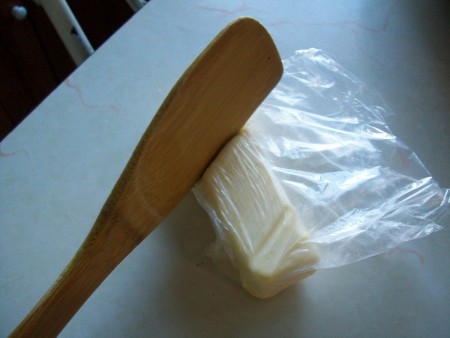 A wooden spoon next to a cube of softened butter.
