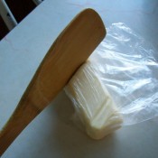 A wooden spoon next to a cube of softened butter.