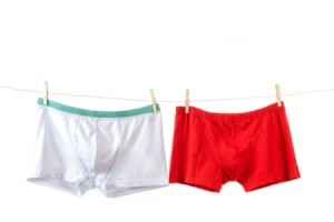 Two pairs of men's boxer briefs in the colors white and red hanging on a clothesline