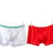 Two pairs of men's boxer briefs in the colors white and red hanging on a clothesline