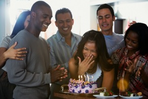 Surprised woman and a group of friends with a cake