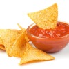 Blended tomato salsa in a glass bowl with chips against a white background
