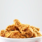 Fried chicken in paper bucket against a white background