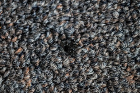 Close up of a cigarette burn on dark carpet