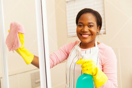 Smiling woman cleaning a shower door