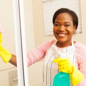 Smiling woman cleaning a shower door