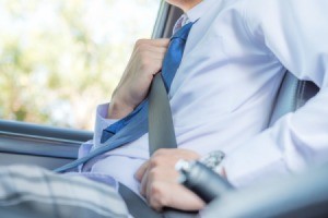 Close-up of the torso of a man wearing a dress shirt and tie bucking a seatbelt