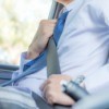 Close-up of the torso of a man wearing a dress shirt and tie bucking a seatbelt